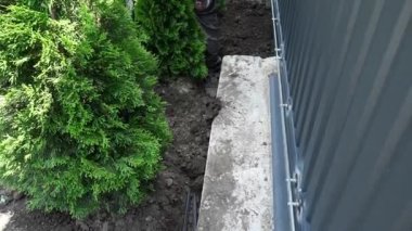 İşçi bir kürekle yere elektrik kablosu döker.