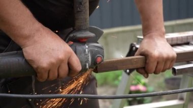 Metal tüpü Angle Grinder kullanarak kesen bir işçi. Parlak kıvılcımlar ve parıltılar