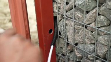 Elektrikçi, kabloyu koruyucu kıvrımlara yerleştirir. Elektrik kabloları için koruyucu kıvrım