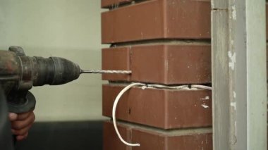 İnşaatçı, çekiç matkapla duvarda delik açıyor. Çekiç delgisine yakın çekim delici delik açıyor.