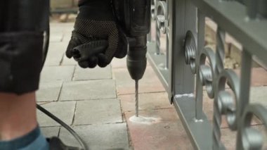 İnşaatçı, çekiç matkapla duvarda delik açıyor. Çekiç delgisine yakın çekim delici delik açıyor.