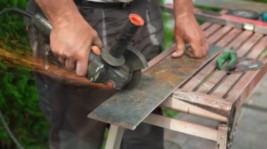 Metal tüpü Angle Grinder kullanarak kesen bir işçi. Parlak kıvılcımlar ve parıltılar