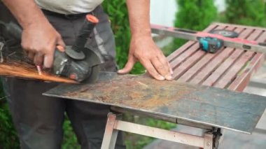 Metal tüpü Angle Grinder kullanarak kesen bir işçi. Parlak kıvılcımlar ve parıltılar