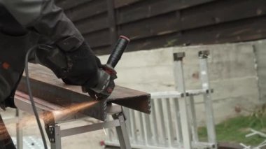 Metal tüpü Angle Grinder kullanarak kesen bir işçi. Parlak kıvılcımlar ve parıltılar