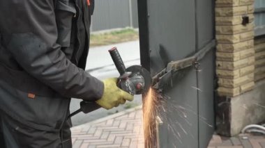 Metal tüpü Angle Grinder kullanarak kesen bir işçi. Parlak kıvılcımlar ve parıltılar