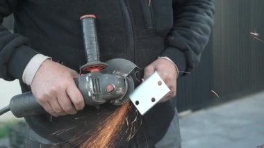 Metal tüpü Angle Grinder kullanarak kesen bir işçi. Parlak kıvılcımlar ve parıltılar