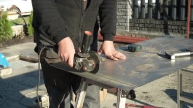 Metal tüpü Angle Grinder kullanarak kesen bir işçi. Parlak kıvılcımlar ve parıltılar