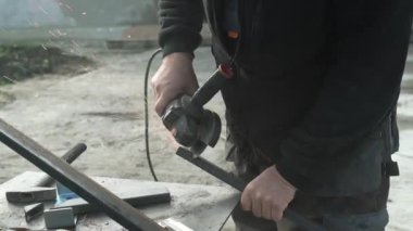 Metal tüpü Angle Grinder kullanarak kesen bir işçi. Parlak kıvılcımlar ve parıltılar