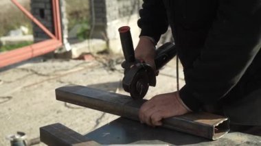 Metal tüpü Angle Grinder kullanarak kesen bir işçi. Parlak kıvılcımlar ve parıltılar