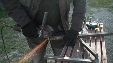 Metal tüpü Angle Grinder kullanarak kesen bir işçi. Parlak kıvılcımlar ve parıltılar