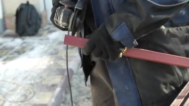 Metal tüpü Angle Grinder kullanarak kesen bir işçi. Parlak kıvılcımlar ve parıltılar