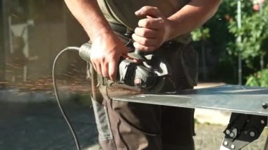 Metal tüpü Angle Grinder kullanarak kesen bir işçi. Parlak kıvılcımlar ve parıltılar