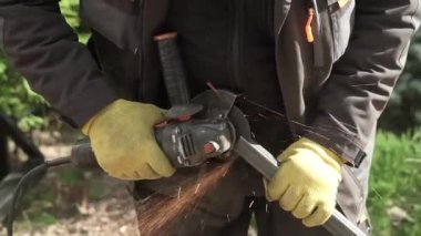 Metal tüpü Angle Grinder kullanarak kesen bir işçi. Parlak kıvılcımlar ve parıltılar