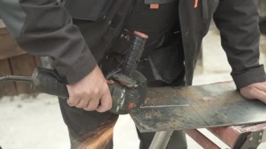 Metal tüpü Angle Grinder kullanarak kesen bir işçi. Parlak kıvılcımlar ve parıltılar