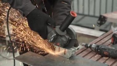 Metal tüpü Angle Grinder kullanarak kesen bir işçi. Parlak kıvılcımlar ve parıltılar
