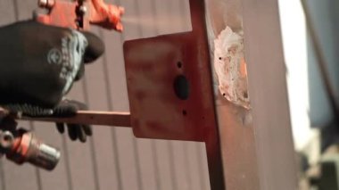 Zanaatkar sprey tabanca kullanarak metal bir yapı boyuyor. İşçi boya spreyi ve kompresörle boya uyguluyor. Ağır çekim.