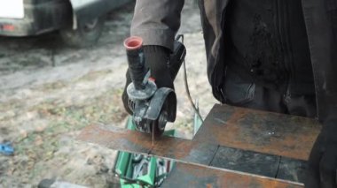 Metal tüpü Angle Grinder kullanarak kesen bir işçi. Parlak kıvılcımlar ve parıltılar