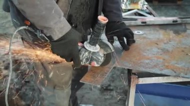 Metal tüpü Angle Grinder kullanarak kesen bir işçi. Parlak kıvılcımlar ve parıltılar