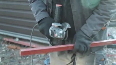 Metal tüpü Angle Grinder kullanarak kesen bir işçi. Parlak kıvılcımlar ve parıltılar