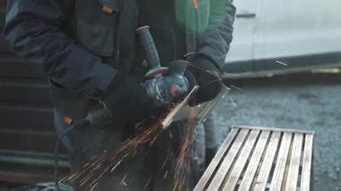 Metal tüpü Angle Grinder kullanarak kesen bir işçi. Parlak kıvılcımlar ve parıltılar