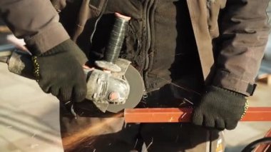 Metal tüpü Angle Grinder kullanarak kesen bir işçi. Parlak kıvılcımlar ve parıltılar