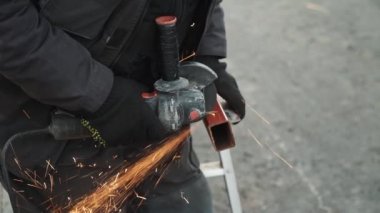 Metal tüpü Angle Grinder kullanarak kesen bir işçi. Parlak kıvılcımlar ve parıltılar