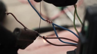 Elektrikçi lehimleme demiriyle elektrik kablolarını lehimliyor. Lehim demiri, kablo tamiri. Usta, gaz lehimleme demiriyle kabloları lehimliyor.