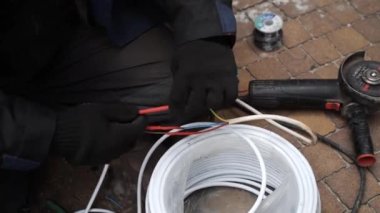 Elektrikçi lehimleme demiriyle elektrik kablolarını lehimliyor. Lehim demiri, kablo tamiri. Usta, gaz lehimleme demiriyle kabloları lehimliyor.