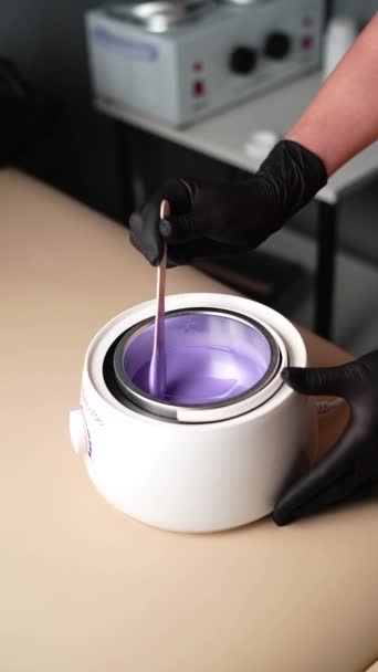 用于脱毛的热紫蜡 脱毛主手在黑色防护手套中的特写用融化的蜡保持着唾液 熔蜡装置 — 图库视频影像