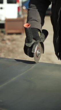 Metal tüpü Angle Grinder kullanarak kesen bir işçi. Parlak kıvılcımlar ve parıltılar