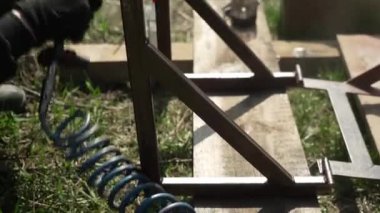 Zanaatkar sprey tabanca kullanarak metal bir yapı boyuyor. İşçi boya spreyi ve kompresörle boya uyguluyor