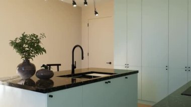 Günışığı ve koyu aksanlı modern ferah parlak mutfak. 3 boyutlu görselleştirme. Asgari cepheli yeşil bir mutfak, siyah bar tabureleri, çekmeceleri ve mutfak aletleriyle dolu bir ada..