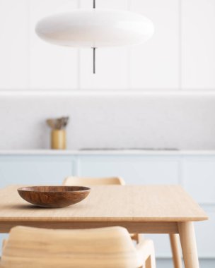 Parlak, havadar mutfak, ahşap bir yemek masası, minimalist bir dekor ve şık bir kolye ışığı. 3d hazırlayıcı