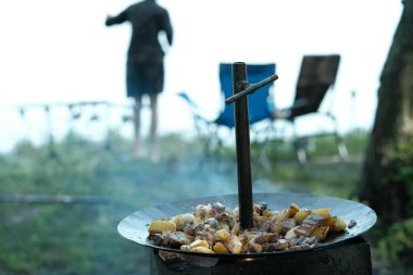 Küp patates, çıtır pastırma şeritleri ve kırmızı soğan dilimleri birbirine karışır. Bazıları kömürleşme ve yağ ile parlaklığı gösterir..
