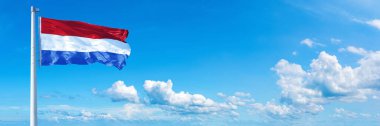 Netherlands Flag - state of Europe, flag waving on a blue sky in beautiful clouds - Horizontal banner