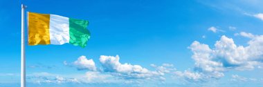 Ivory Coast Flag - state of Africa flag waving on a blue sky in beautiful clouds - Horizontal banner