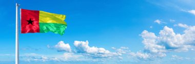 Guinea-Bissau Flag - state of Africa, flag waving on a blue sky in beautiful clouds - Horizontal banner