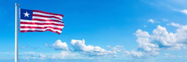 Liberia Flag - state of Africa, flag waving on a blue sky in beautiful clouds - Horizontal banner