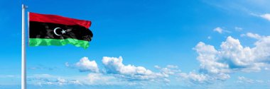 Libya Flag - state of Africa, flag waving on a blue sky in beautiful clouds - Horizontal banner