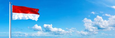 Indonesia flag - state of Asia, flag waving on a blue sky in beautiful clouds - Horizontal banner