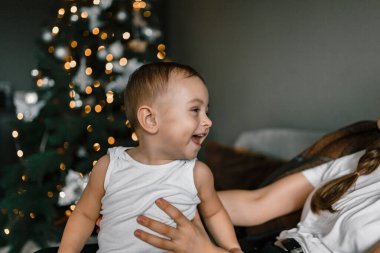 Mutlu küçük bir çocuğun Noel ağacının arka planına yakın plan çekimi. Çocuk rahat bir şenlik ortamında evde. Kış tatili ve insanların konsepti