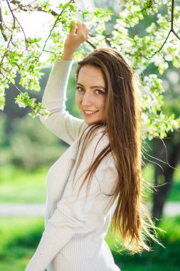 Büyüleyici genç bir kadın varlığıyla bir bahar parkını şereflendiriyor, yenilenme, aşk, mutluluk ve kadınlığın temalarını sembolize ediyor.