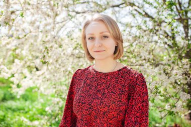 Güneşli bir bahar gününde çiçek bahçesinde poz veren sevimli bir kadın. Doğayla bütünlük kavramı