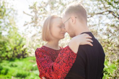 Sevgi dolu bir çiftin portresi rahatlatıcı ve güzel bahar havasının ve parlayan güneşin tadını çıkarıyor. Aile kavramı ve doğa ile birlik.