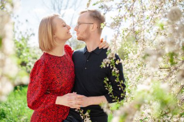 Mutlu çift güneşli bir bahar gününde dişleriyle gülüyor ve sarılıyor. Çiçek manzarası ve doğa konsepti