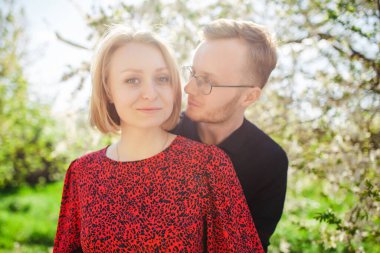 Sarışın bir kadın ve bir erkek, güneşli bir bahar gününde çiçek açan bir vişne ağacının yanında neşeyle vakit geçiriyorlar. Aşkı, aileyi ve mutluluğu simgeliyor.