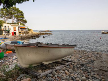 Cala Alguer 'de Palamlar, Costa Brava, İspanya' da geleneksel balıkçı evleri olan bir teknenin ana görüntüsü. Tatil kavramı.