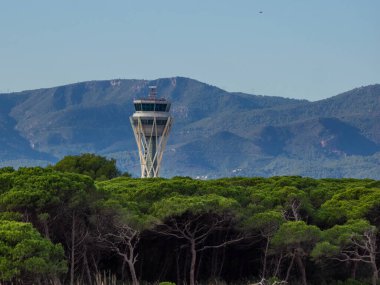 İspanya 'nın Barcelona kentindeki El Prat havaalanının kontrol kulesinin ormanlık alanından gündüz görüntüsü..