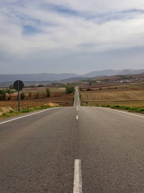 Güzel bir sonbahar gününde sıcağın puslu olduğu kurak İspanyol arazisinde sonsuz düz bir yolun klasik panoramik manzarası..