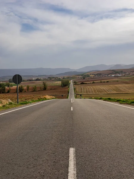 stock image Classic panoramic view of an endless straight road through the arid Spanish landscape with a heat haze on a beautiful autumn day.